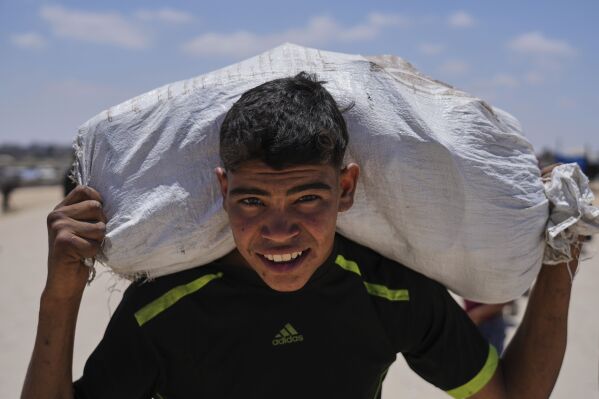 A Palestinian youth carries food and humanitarian aid delivered by the U.S.-backed Gaza Humanitarian Foundation, after receiving the supplies in Rafah, as he arrive in Khan Younis, southern Gaza Strip, on Wednesday, May 28, 2025. (AP Photo/Abdel Kareem Hana)