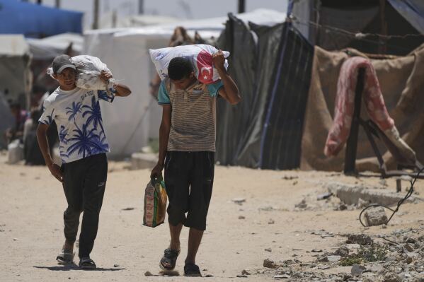 Palestinians carry food and humanitarian aid delivered by the U.S.-backed Gaza Humanitarian Foundation, after receiving the supplies in Rafah, as they arrive in Khan Younis, southern Gaza Strip, on Wednesday, May 28, 2025. (AP Photo/Abdel Kareem Hana)