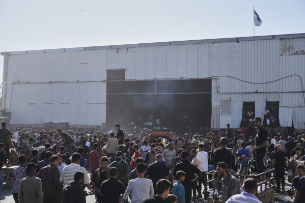 Palestinians storming a U.N. World Food Program warehouse and carry bags of flour in Zawaida, Central Gaza Strip, on Wednesday, May 28, 2025. (AP Photo/Abdel Kareem Hana)